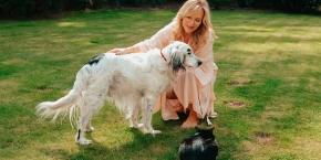 Lady crouching by a dog and cat on a green garden lawn