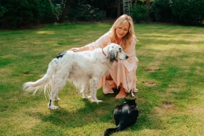 Lady crouching by a dog and cat on a green garden lawn